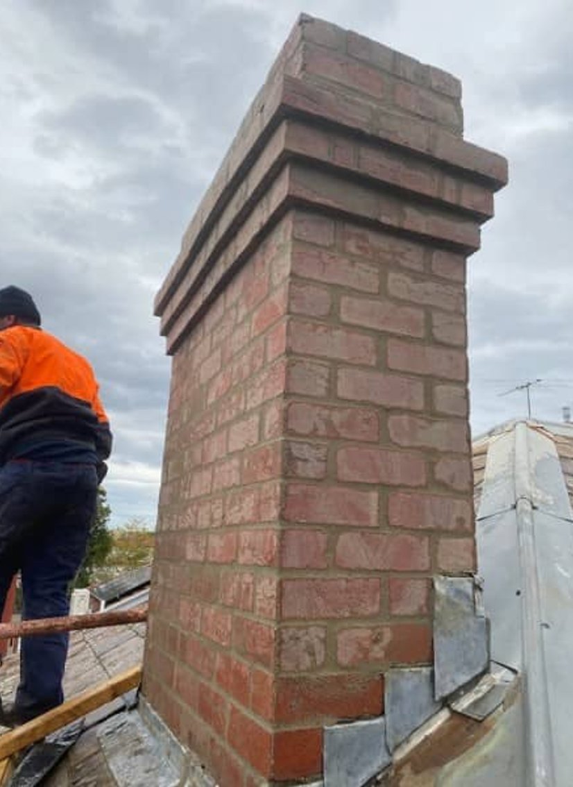 Decorative red brick chimney with corbelled top and lead roof flashing
