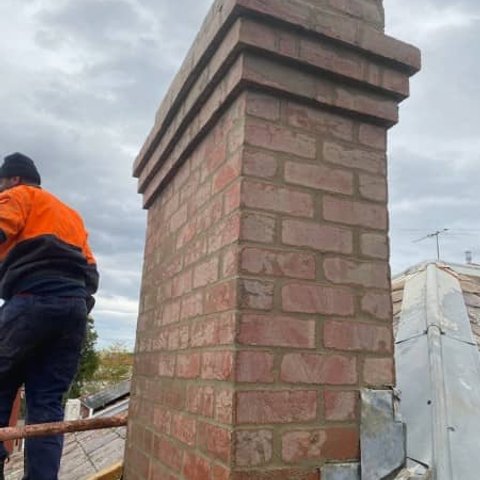 Decorative red brick chimney with corbelled top and lead roof flashing
