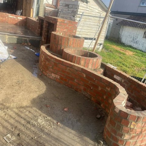 Curved serpentine garden brick wall with circular brick planters