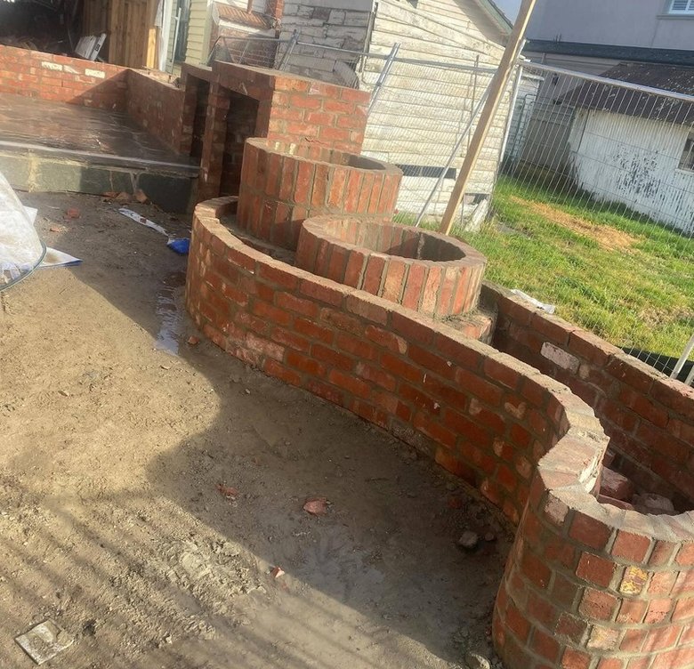 Curved serpentine garden brick wall with circular brick planters