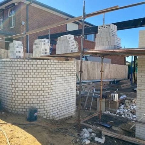 Curved cream brick wall and tall pillar on a scaffolded residential build