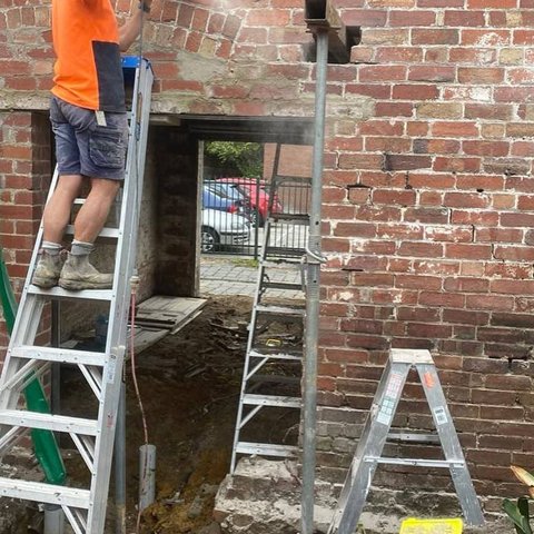 Bricklayer cutting a structural opening in a period red brick wall