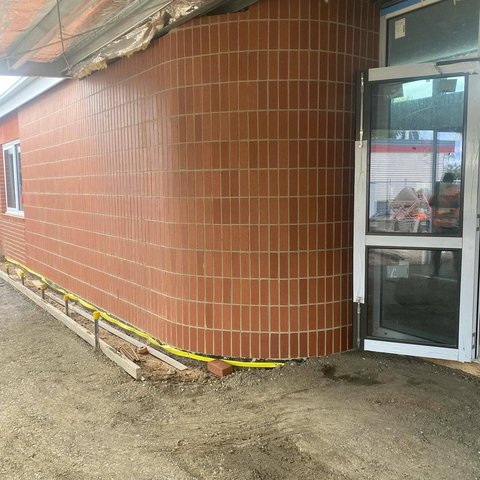 Curved orange brick wall laid in a vertical stack bond pattern