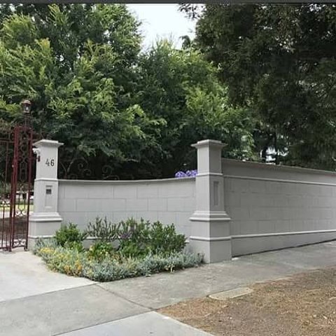 Rendered grey front fence with curved section and decorative pillars