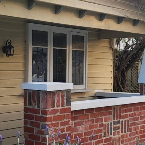 Decorative red brick pillar and patterned front fence with white capping