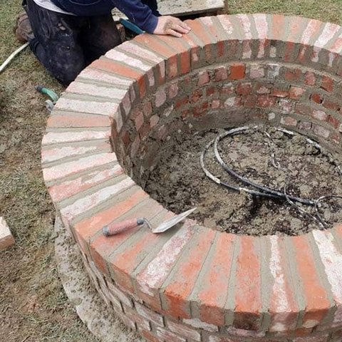 Circular brick planter or fire pit with radial header course brickwork