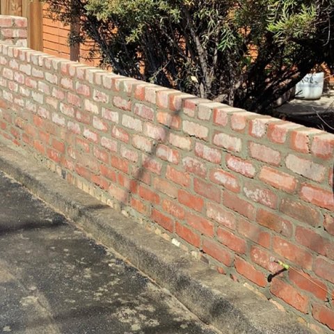 Low rustic red brick garden wall with flat brick capping