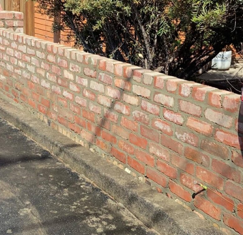 Low rustic red brick garden wall with flat brick capping