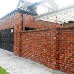 High red brick fence with black panel garage door High red brick fence with black panel garage door